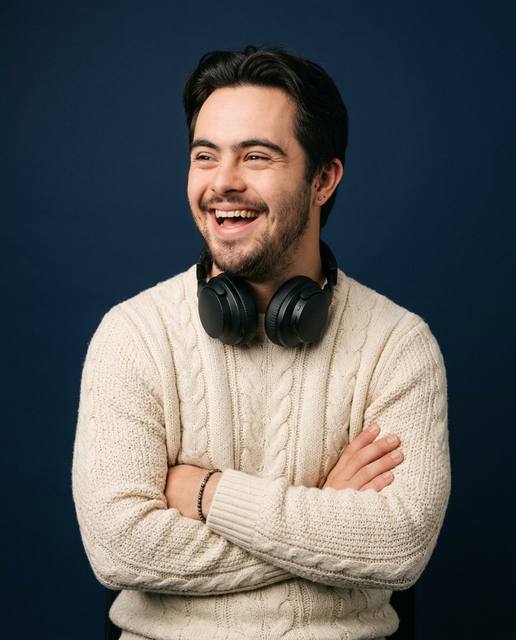 Young man laughing with headphones around his neck